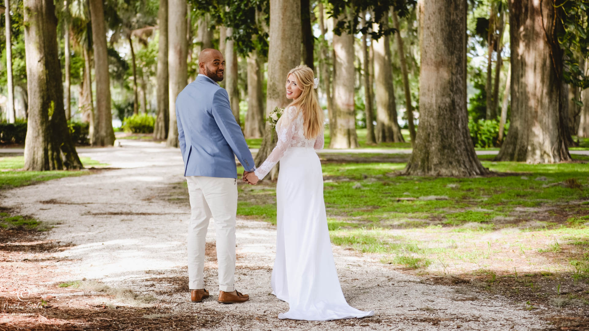 Florida Garten Hochzeit, Brautpaar hält sich die Hände unter Bäumen