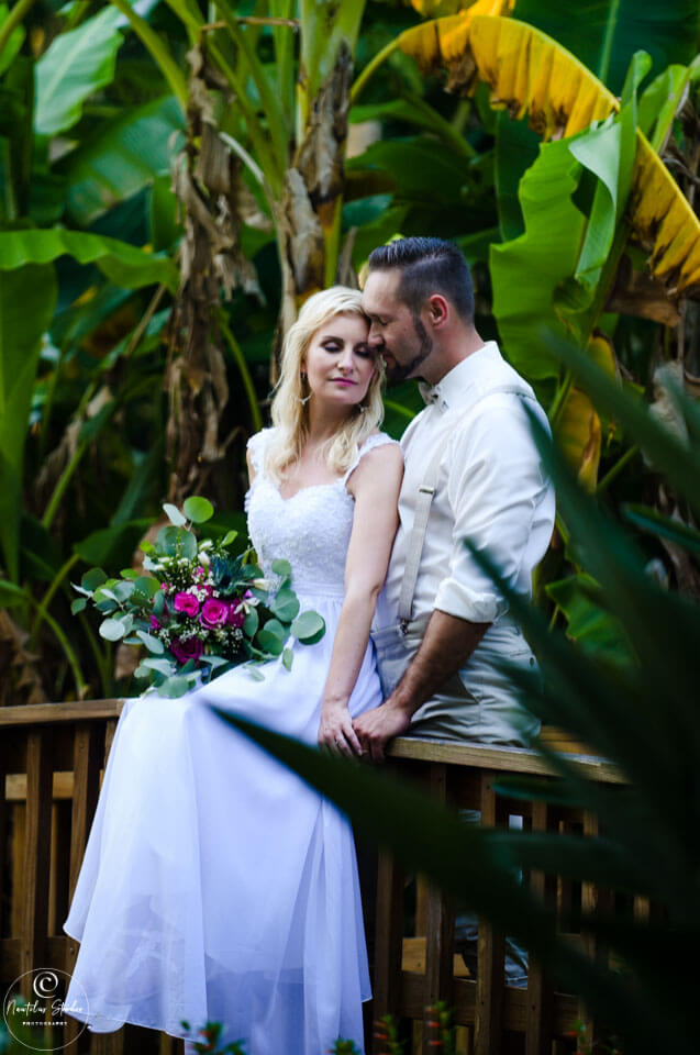 Hochzeitspakete in Florida Gärten, Brautpaar umgeben von tropischen Pflanzen