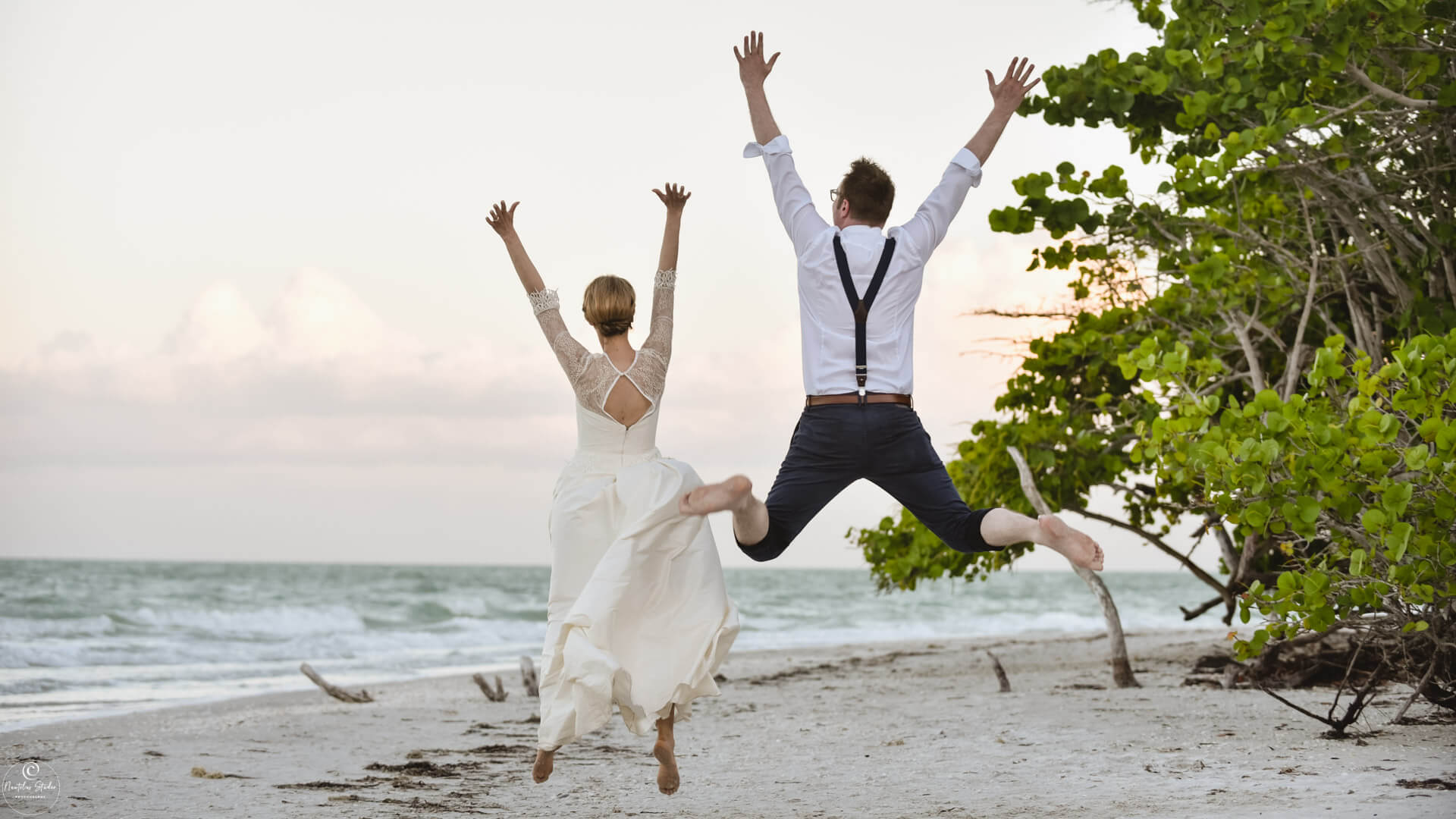 Heiraten zum Schnäppchenpreis in Florida, Foto von Brautpaar am Strand das in die Luft springt