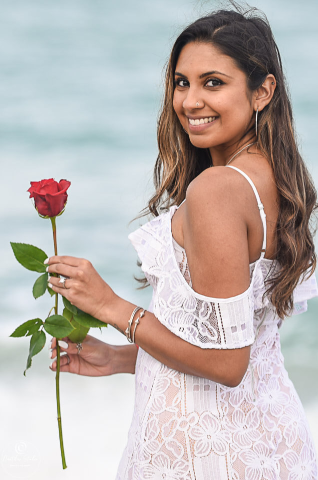 Foto von Frau mit roter Rose am Strand