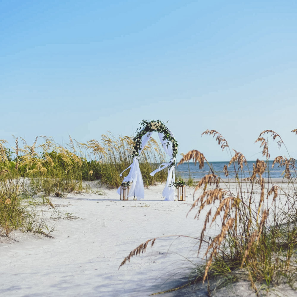 Foto von einem Hochzeitsbogen dekoriert mit weissen Rosen am Strand von Florida
